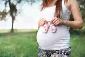 Gratis foto een deel van de zwangere vrouw met kleine schoenen voor baby