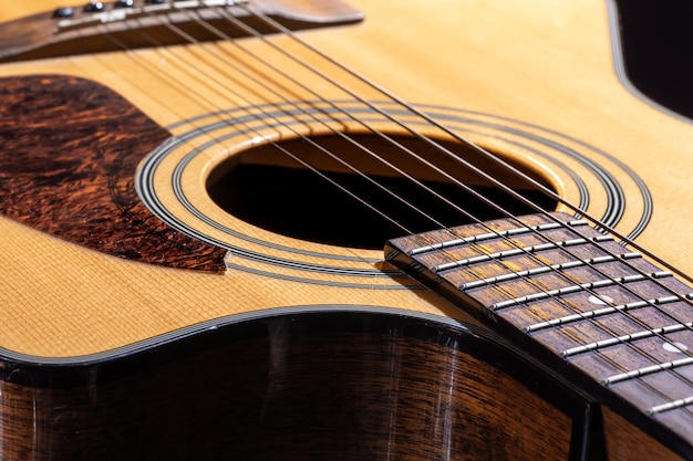 Een deel van een akoestische gitaar, gitaar toets met snaren op een zwarte achtergrond.