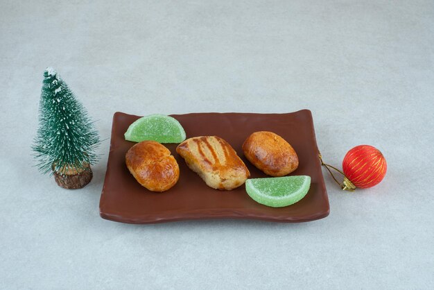 Een donker bord met zoete gebakjes met marmelade en kerstspeelgoed.