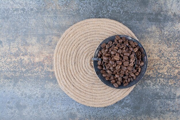 Een donkere kop vol koffiebonen op marmeren achtergrond. Hoge kwaliteit foto