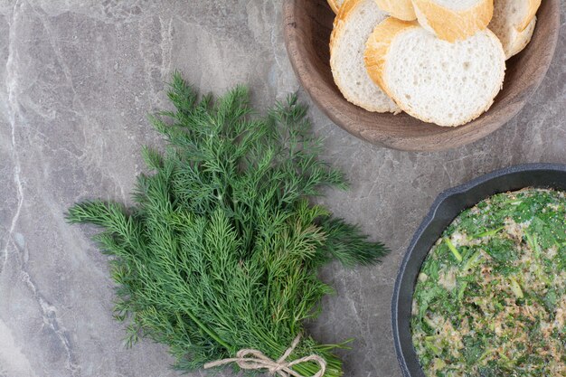 Een donkere pan gebakken eieren met Groenen en wit brood op marmeren achtergrond. Hoge kwaliteit foto