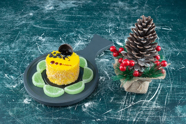 Een donkere pan met gele verse cake en grote kerst dennenappel. Hoge kwaliteit foto