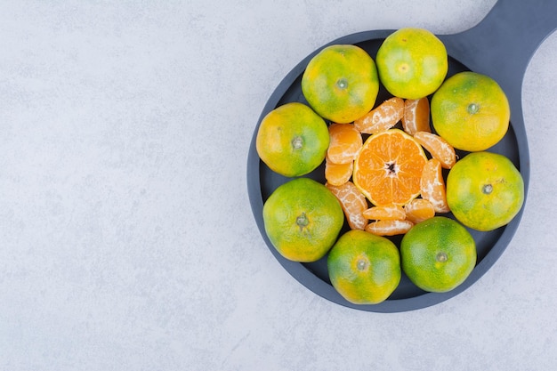 Een donkere pan van zure mandarijnen op witte achtergrond. Hoge kwaliteit foto