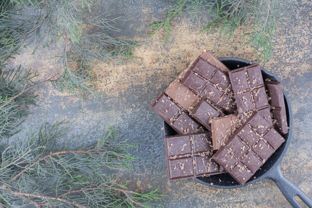 Een donkere pan vol gesneden chocolaatjes op marmeren achtergrond. Hoge kwaliteit foto