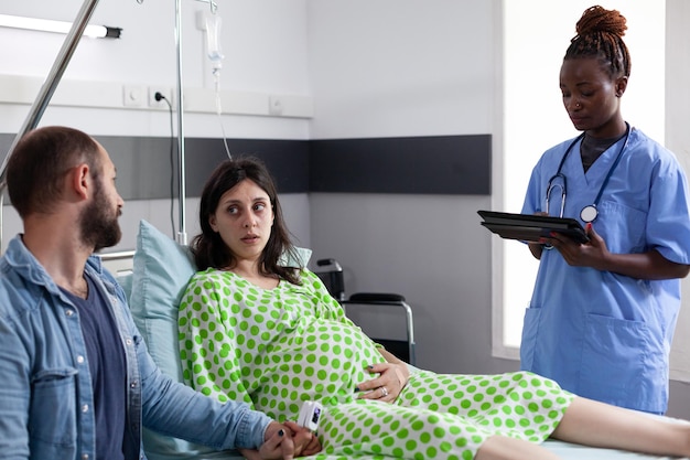 Gratis foto een echtpaar ontvangt medische hulp van een afro-amerikaanse verpleegster voor de bevalling in de ziekenhuisafdeling.