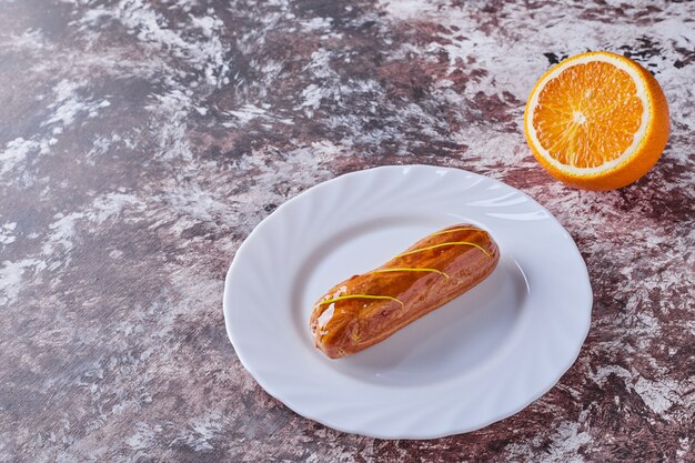 Een eclair met karamelsiroop in een wit bord.