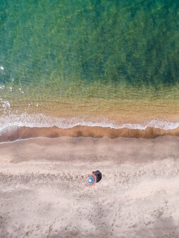 Een eenzame strandparaplu op het zandstrand, vlakke luchtmeningsachtergrond