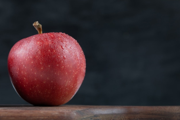 Een enkele rode appel op een houten schotel