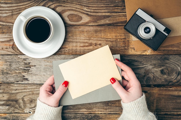 Gratis foto een envelop en een vel papier in vrouwelijke handen op een houten bovenaanzicht als achtergrond