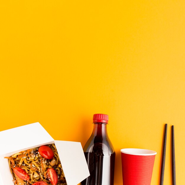 Een fles frisdrank met Chinees fastfood.