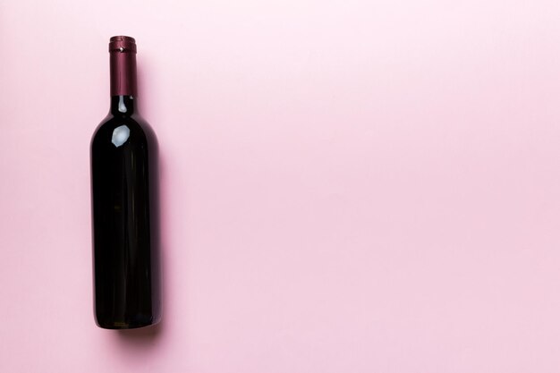 Een fles rode wijn op gekleurde tafel. platliggend, bovenaanzicht met kopieerruimte.