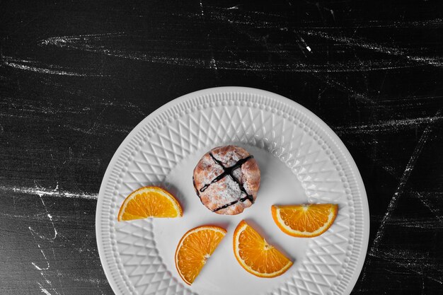 Een gebakje broodje met chocoladesiroop geserveerd met stukjes sinaasappel.