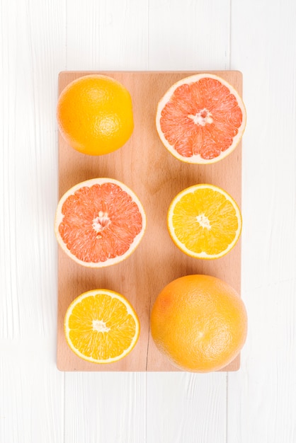 Een gehalveerde sinaasappelen en grapefruits op snijplank over witte tafel