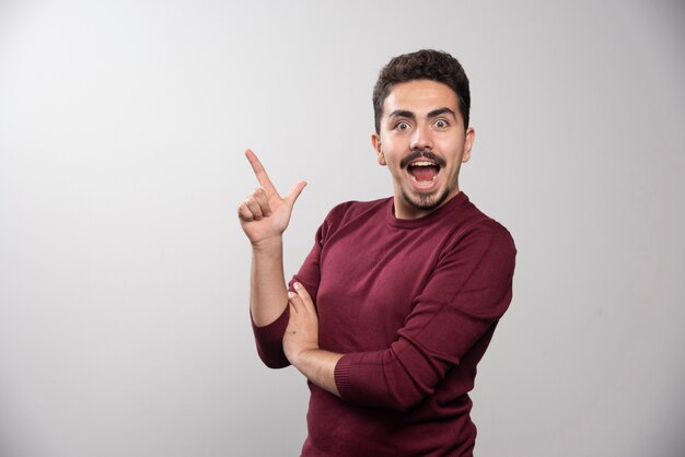 Een gelukkig brunette man met een vinger omhoog en poseren.