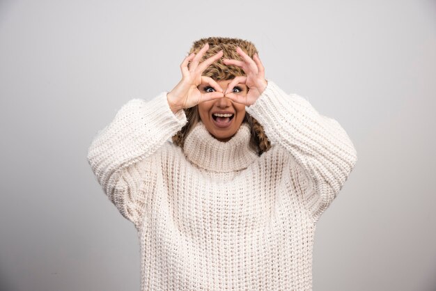 Gratis foto een gelukkige vrouw in mooie hoed doet ok gebaar als een verrekijker.