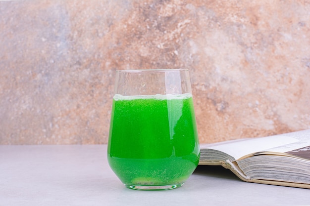 Gratis foto een glas groene cocktail op witte lijst.