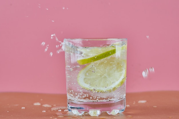 Een glas koude verfrissende limonade op roze oppervlak