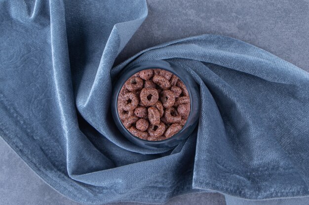 Een glas maïs ringen op een stuk stof, op de blauwe achtergrond.