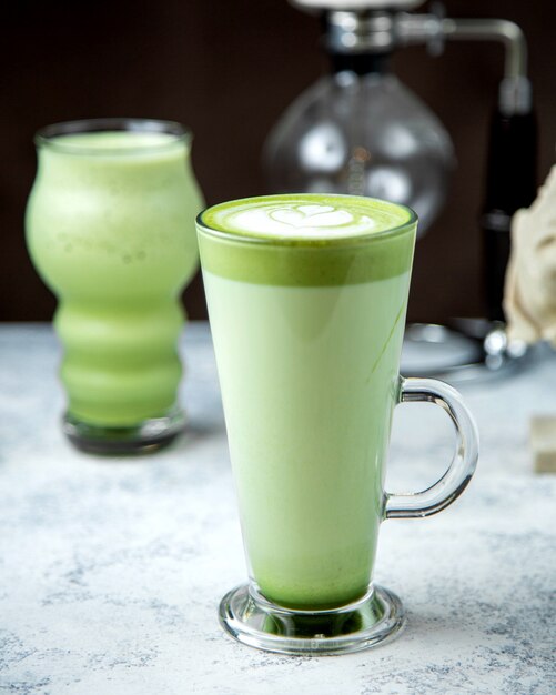 Een glas matcha groene thee met latte kunst erop