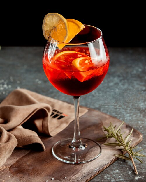 Een glas rode cocktail gegarneerd met stukjes sinaasappel