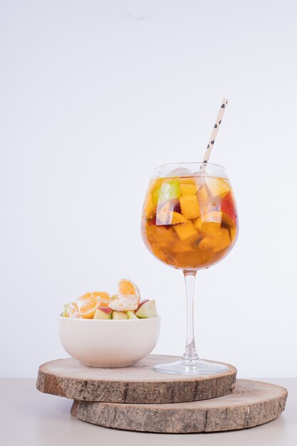 Een glas sap en fruitschaal witte tafel.