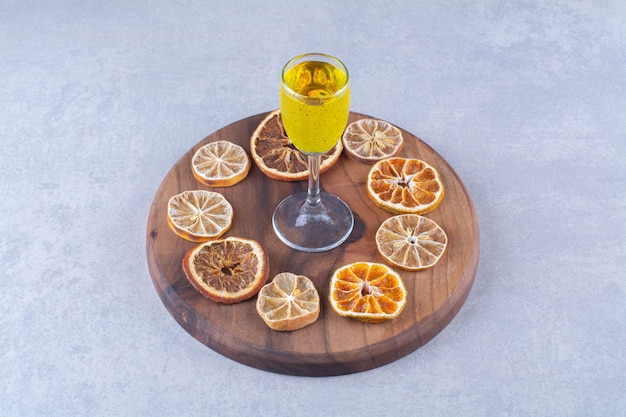 Gratis foto een glas sap, gedroogde sinaasappel- en citroenschijfjes aan boord, op de marmeren achtergrond.