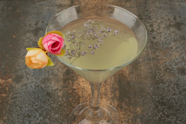 Een glas sappige limonade en rozen op marmeren oppervlak.