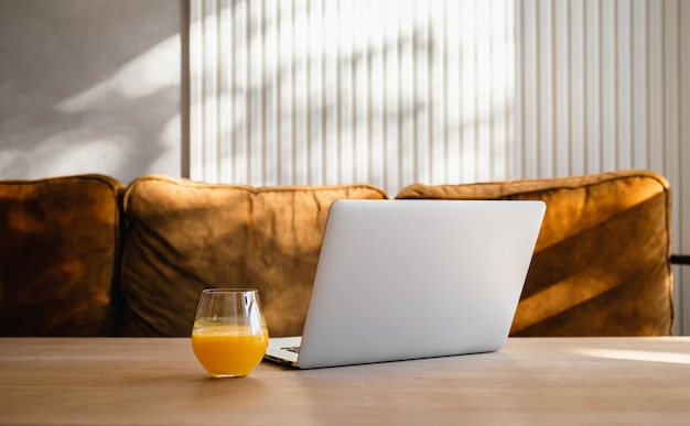 Een glas sinaasappelsap bij de laptop op tafel