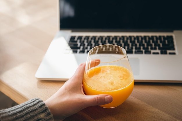 Een glas sinaasappelsap en een laptop het concept van werk en studie