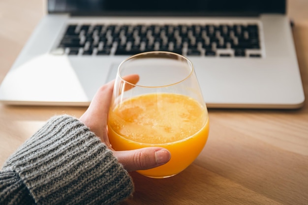 Een glas sinaasappelsap en een laptop het concept van werk en studie