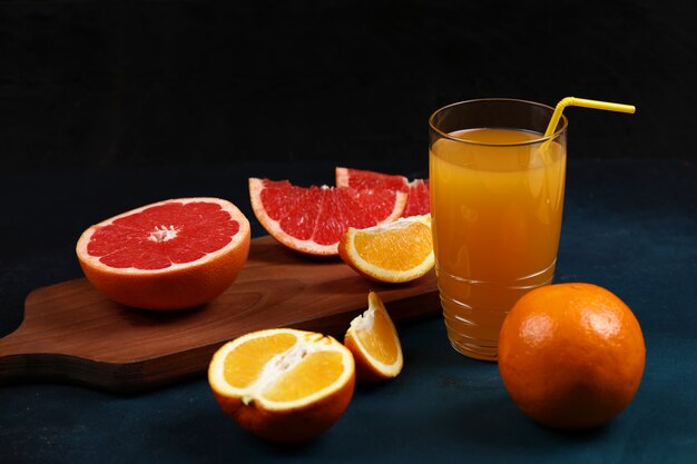 Een glas sinaasappelsap met gesneden sinaasappel en grapefruit.