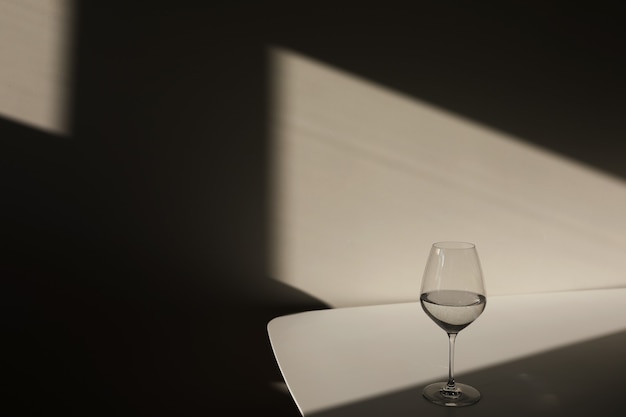 Een glas water op een witte achtergrond met een schaduw clair-obscur uit het raam close-up kopie ruimte