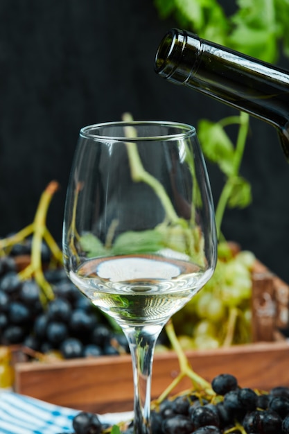 Een glas witte wijn met een tros rode druiven.