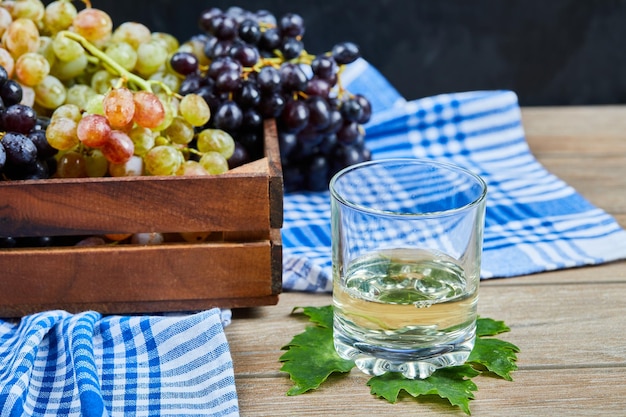 Gratis foto een glas witte wone op houten tafel met druiven.