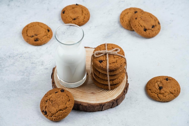 Een glazen beker met chocoladekoekjes op een houten bureau.