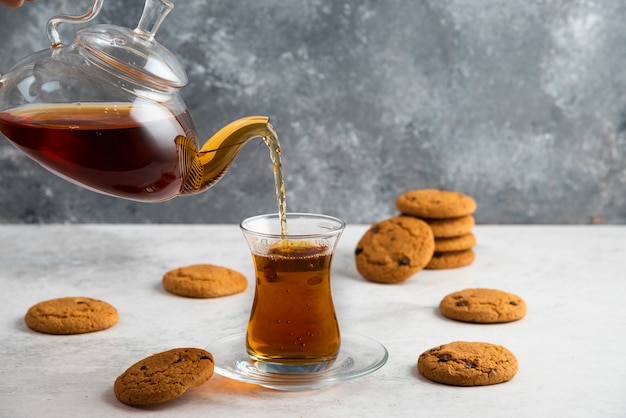 Een glazen kopje thee met heerlijke koekjes.