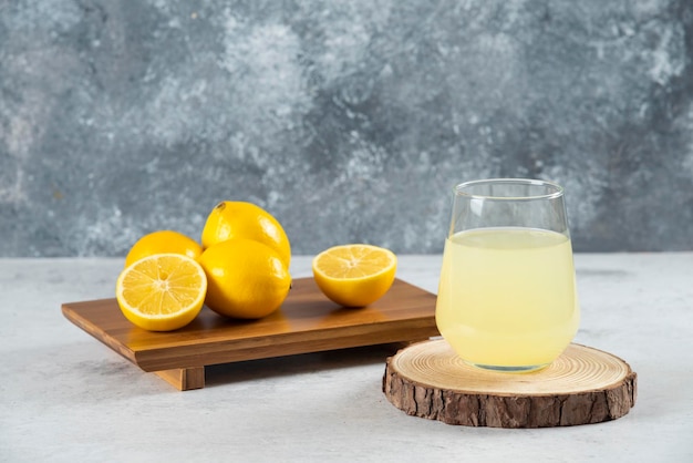 Een glazen kopje vers citroensap op een houten bord.