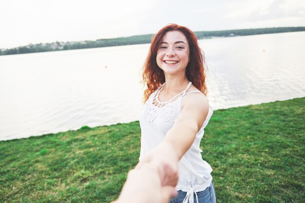 Een glimlachende gelukkige vrouw met een speelse uitdrukking en een hand met haar man.