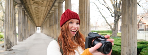 Een glimlachende toeristenfotograaf maakt een foto tijdens haar reis, houdt een professionele camera vast en maakt
