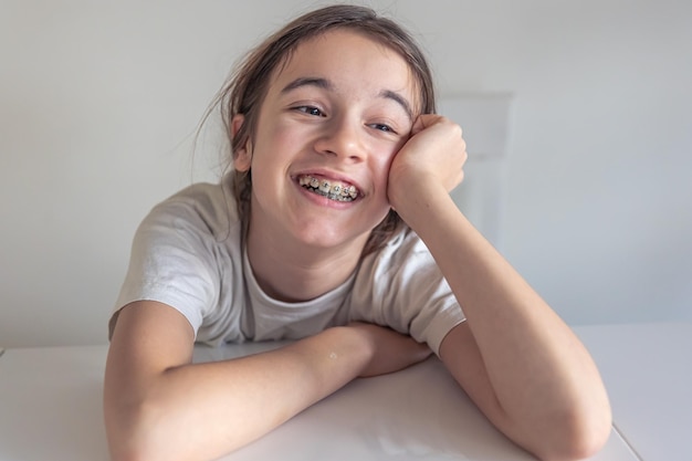 Een grappig tienermeisje kijkt naar de camera en demonstreert beugels op haar tanden