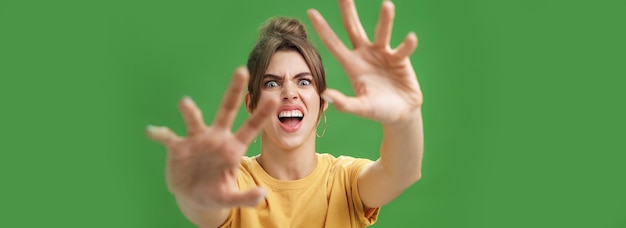 Gratis foto een grappige emotionele vrouw die een grappig gezicht trekt en de handen naar voren trekt om aan te vallen of iets fronsend open te grijpen
