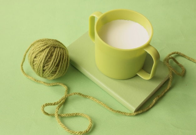Een groene kop melk op het boek en een groene draadbal eromheen.
