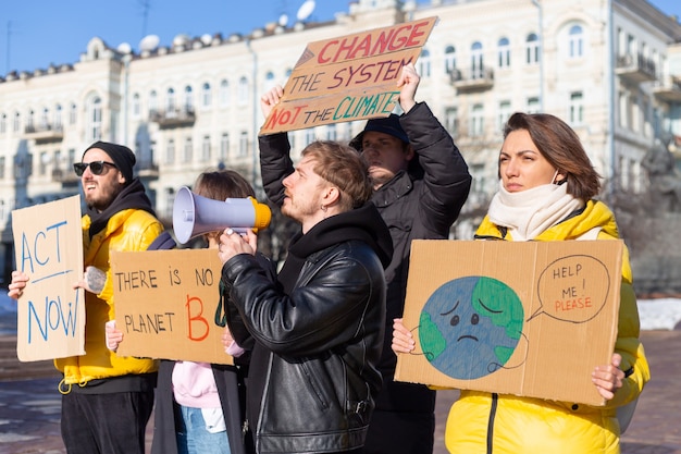 Een groep mensen met spandoeken en een megafoon in de hand protesteert op het stadsplein voor svae planet clean world act now