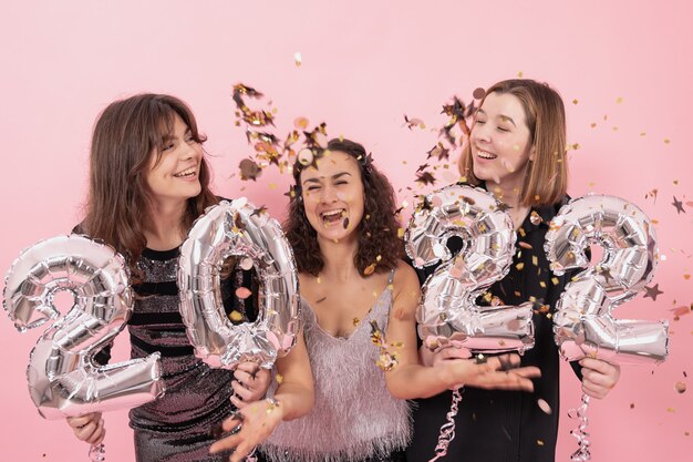 Een groep vrolijke meisjes met zilveren ballonnen in de vorm van cijfers