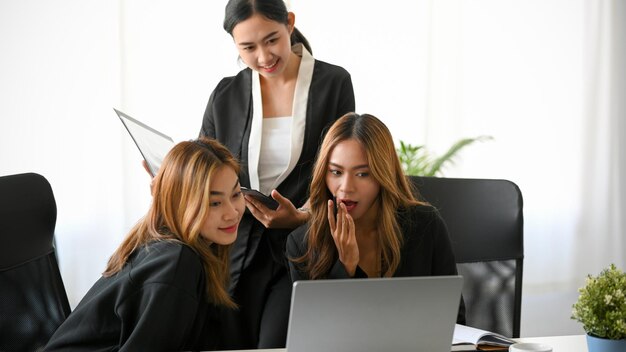 Een groep zakenvrouwen verzamelde zich op kantoor en keek naar grappige video's op een laptopcomputer
