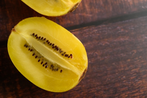 Gratis foto een half-cut gele kiwi op een houten tafel.