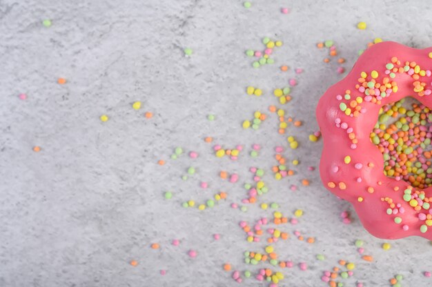 Een halve aardbeidoughnut verfraaide suikerglazuur en besprenkeling op de vloer