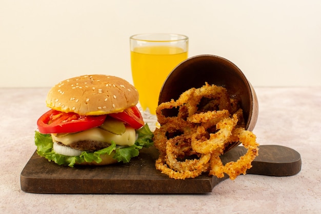 Een hamburger van het vooraanzichtvlees met kaassap en groene salade en kippenvleugels op de houten lijst