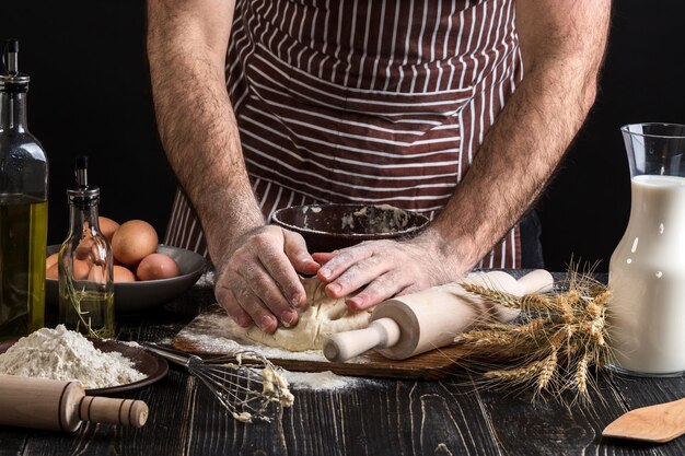 Een handvol bloem met ei op een rustieke keuken. Kneed het deeg tegen de achtergrond van mannenhanden. Ingrediënten voor het koken van meelproducten of deegbrood, muffins, taart, pizzadeeg. Ruimte kopiëren