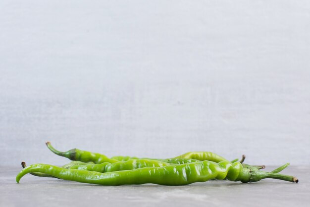 Een handvol groene paprika's op marmer.